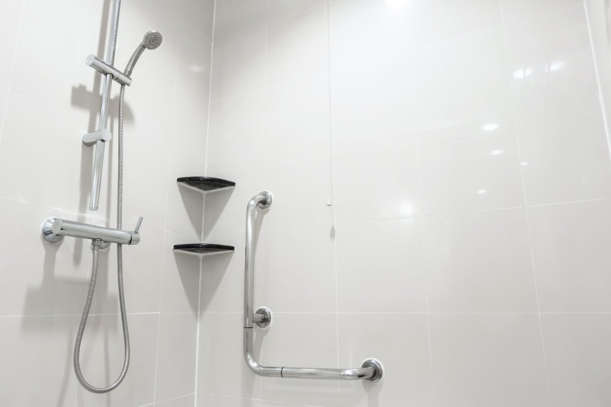Modern shower with grab bars and shelves.