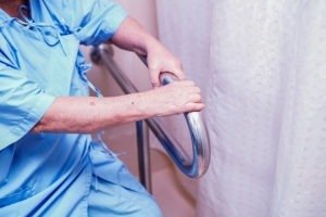 Hands gripping a safety bar in a bathroom.