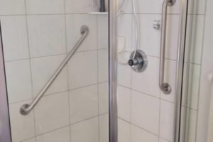 Accessible shower with grab bars and tiled walls.