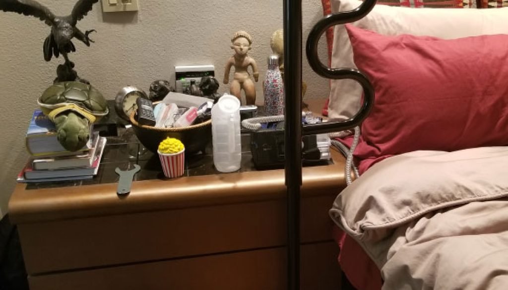 Cozy bedroom scene with various items on nightstand.