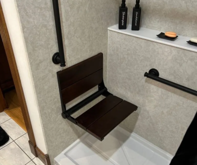 Accessible shower with foldable seat and grab bars.