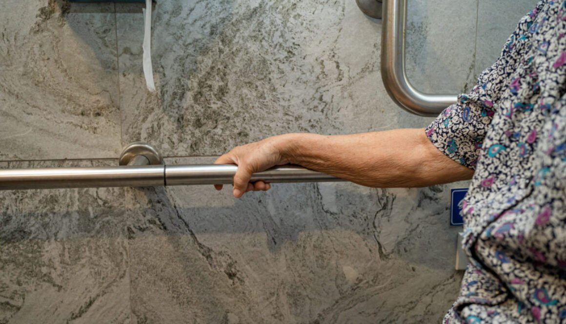 Hand gripping a metal support bar.