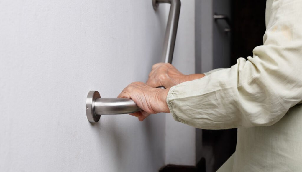 Hands gripping a metal grab bar for support.