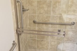 Accessible shower with grab bars and glass door.