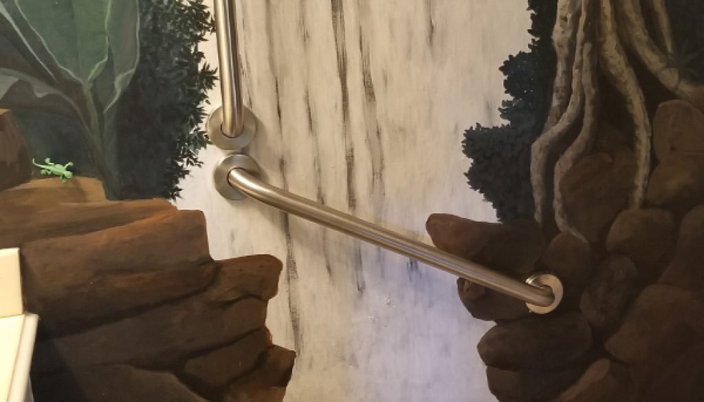 Bathroom with waterfall mural and grab bar.